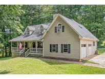 Charming two-story home with a welcoming porch, attached garage, and beautiful landscaping at 1580 Lower Burris Rd, Canton, GA 30114