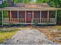 Charming log cabin featuring a cozy front porch and stone chimney at 5642 Dorsett Shoals Rd, Douglasville, GA 30135