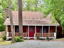 Charming log cabin-style home with a red front door and inviting front porch at 5642 Dorsett Shoals Rd, Douglasville, GA 30135