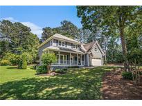 Charming two-story home featuring a welcoming front porch and lush, mature landscaping on a sunny day at 1655 Peachcrest Dr, Lawrenceville, GA 30043