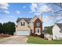 Charming two-story home featuring a brick facade, a two-car garage, and a well-manicured front lawn at 5686 Grindstone Dr, Buford, GA 30518