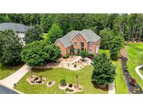 Beautiful brick home with lush lawn and landscaping featuring mature trees and colorful plants at 805 Cog Hl, Mcdonough, GA 30253