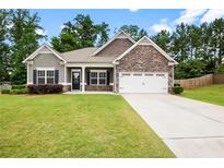 Charming single-Gathering home boasts stone accents, a two-car garage, and a well-manicured front lawn at 132 Berkleigh Trails Dr, Hiram, GA 30141