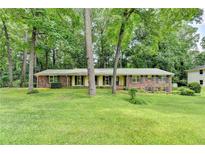 Charming brick home with a lush green lawn and mature trees providing shade and curb appeal at 1970 Fisher Ne Trl, Atlanta, GA 30345