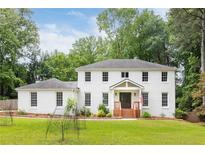 Inviting two-story white brick home featuring a charming front porch and well-manicured lawn at 5070 Hensley Dr, Atlanta, GA 30338