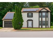 Inviting two-story home featuring solar panels, brown trim, a well-manicured lawn, and an attached garage at 3255 Hunters Crossing Pt, Lithonia, GA 30038