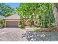 Charming home featuring a stone front, two-car garage and a lush, tree-lined landscape, inviting curb appeal at 110 Boulder Dr, Roswell, GA 30075