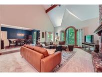 Spacious living room featuring a vaulted ceiling, fireplace, and large window with backyard views at 110 Boulder Dr, Roswell, GA 30075
