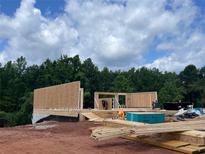 New home under construction with wood framing and beautiful treed backdrop at 3063 Reserve Ct Sw, Conyers, GA 30094