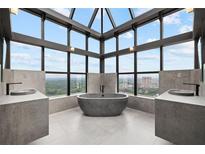 Bright bathroom featuring modern sinks, a stylish tub and window views overlooking the city at 2828 Peachtree Nw Rd # P 3300, Atlanta, GA 30305