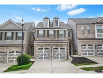 Charming brick townhome featuring a two-car garage and well-maintained landscaping at 228 Stone Park Dr, Woodstock, GA 30188