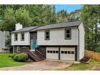Charming two-story home with a beautifully landscaped front yard, a blue front door, and an attached two-car garage at 230 Sheringham Dr, Roswell, GA 30076