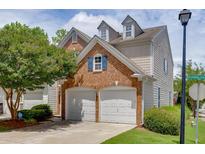 Two-car garage with brick facade and dormer windows, part of a charming townhome with a landscaped yard at 2421 Elkhorn Ter, Duluth, GA 30096