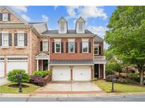 Beautiful brick townhome with two-car garage, dormer windows, and well-manicured landscaping at 11945 Dancliff Trce, Alpharetta, GA 30009