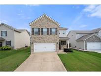 Two-story brick home with a two car garage and a well manicured lawn on a bright sunny day at 7644 Rudder Cir, Fairburn, GA 30213
