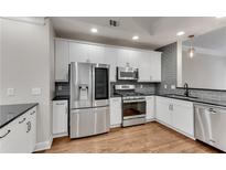 Modern kitchen featuring white cabinets, stainless steel appliances, granite countertops, and a light grey backsplash at 793 Inman Mews Ne Dr, Atlanta, GA 30307