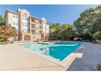 Bright pool area with condo building and mature landscaping on a sunny day at 220 Renaissance Ne Pkwy # 2220, Atlanta, GA 30308