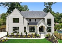 Charming two-story home features a white brick facade, black framed windows, manicured lawn and well-designed landscaping at 1312 Becket Ne Dr, Brookhaven, GA 30319