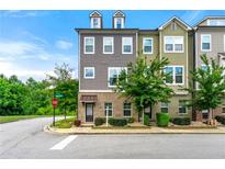 A well-maintained three-story townhome showcasing a mix of brick and siding accents on a landscaped corner lot at 2140 Colvin Nw Ct, Atlanta, GA 30318