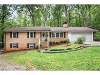 Charming brick home featuring a well-manicured lawn and attached two-car garage nestled in a serene, wooded setting at 505 Samaritan Dr, Cumming, GA 30040