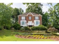 Charming two-story brick home with a landscaped front yard and wooden retaining wall at 1350 Rivershyre Pkwy, Lawrenceville, GA 30043