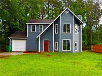 Charming two-story home featuring blue siding, a red front door, and a well-maintained front yard at 1081 Forest Path, Stone Mountain, GA 30088