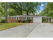 Charming brick home featuring a garage and carport, surrounded by mature trees and a spacious driveway at 3152 Ridgecrest Dr, Powder Springs, GA 30127