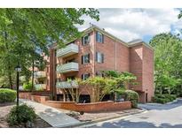 Brick condo building with white balconies, black shutters, and lush green landscaping at 302 Ridley Howard Ct # 302, Decatur, GA 30030
