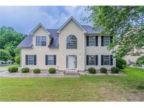 Charming two-story home with a well-manicured lawn and symmetrical landscaping in a suburban neighborhood at 6181 E Fayetteville Dr, Riverdale, GA 30296
