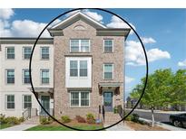 Beautiful three-story brick townhome featuring manicured lawn and welcoming entrance at 1621 Wellborn Walk, Suwanee, GA 30024