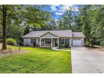 Charming single-story home with manicured lawn, mature trees, and an attached one-car garage at 5706 Forest Pl, Acworth, GA 30102