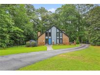 Charming exterior elevation of brick home features a blue front door and lush, green landscaping at 1605 Saint Tropez Way, Atlanta, GA 30350