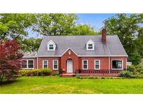 Charming brick home with a well-maintained lawn, mature trees and dormer windows at 407 E College E St, Bowdon, GA 30108
