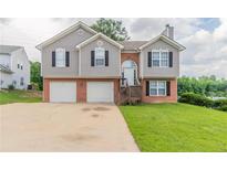 Charming split-level home featuring a two-car garage, neutral siding, and a well-maintained front lawn at 725 Signature Trce, Palmetto, GA 30268