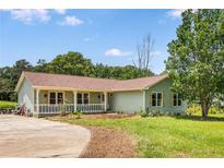 Charming one-story home with a covered porch, green siding, mature trees, and a well-maintained lawn at 107 Bowen Rd, Stockbridge, GA 30281