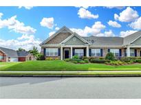 Charming brick townhome featuring a lush green lawn, tidy landscaping, and inviting curb appeal at 3411 Lindenridge Dr, Buford, GA 30519