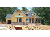 Under construction two-story home with a yellow facade, brick foundation, and black shingled roof at 4545 Greyson Manor Dr, Cumming, GA 30041