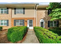 Inviting townhome featuring a brick facade, black shutters, and lush green landscaping at 406 Northdale Ct, Lawrenceville, GA 30046