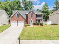 Charming two-story brick home featuring a well-manicured lawn, two-car garage, and classic architectural details at 6317 Selborn Sw Dr, Atlanta, GA 30331