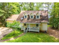 Charming yellow home with a welcoming front porch, surrounded by lush greenery at 9018 Lakeview Pkwy, Villa Rica, GA 30180