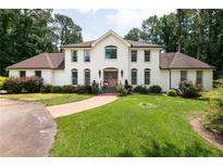 Stunning two-story white home featuring a lush green lawn, well-manicured landscaping, and a grand entrance at 1908 Musket Ct, Stone Mountain, GA 30087