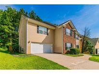Two-story home featuring brick and siding exterior, attached garage, and a well-maintained front lawn at 5018 Upper Elm St, Atlanta, GA 30349