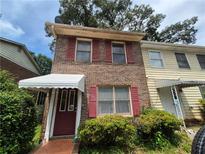 Charming two-story brick home with red shutters, a covered entryway, and a well-kept front yard at 964 Glynn Oaks Dr, Clarkston, GA 30021