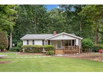 Charming single story home with a covered porch and lush, green landscaped front yard at 307 Little Hickory Ln, Woodstock, GA 30189