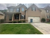 Charming two-story home with a well-manicured lawn and attached two-car garage at 443 Strawberry Walk, Loganville, GA 30052