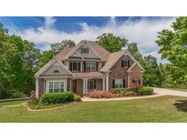Beautiful two-story home featuring a brick and stone facade, covered porch, and meticulously maintained landscaping at 893 Somersby Dr, Dallas, GA 30157