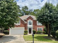 Charming two-story brick home with manicured lawn, two car garage, and mature trees at 5015 Riverthur Pl, Peachtree Corners, GA 30096