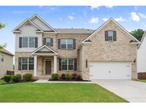 Charming brick two-story home features a manicured lawn and a two-car garage at 5575 Mirror Lake Dr, Cumming, GA 30028