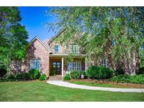 Charming two-story brick home boasts a covered porch and beautifully landscaped front yard at 197 Westbrook Rd, Carrollton, GA 30116