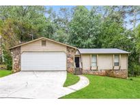 Charming single-story home featuring a two-car garage, stone accents, and well-maintained lawn at 1024 Stone Mill Run, Lawrenceville, GA 30046